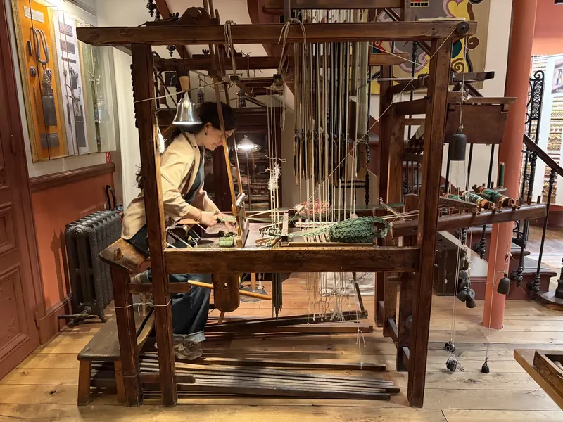 Artisane travaillant sur un métier à tisser dans les ateliers Declercq Passementiers.